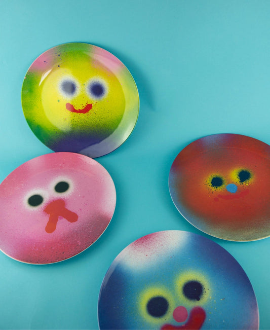 Vier Melamin-Teller mit Motiven von Jon Burgerman aus der Serie Milkshake, Buttercake, Blue und Bowie mit leuchtenden Spray-Paint-Farbverläufen