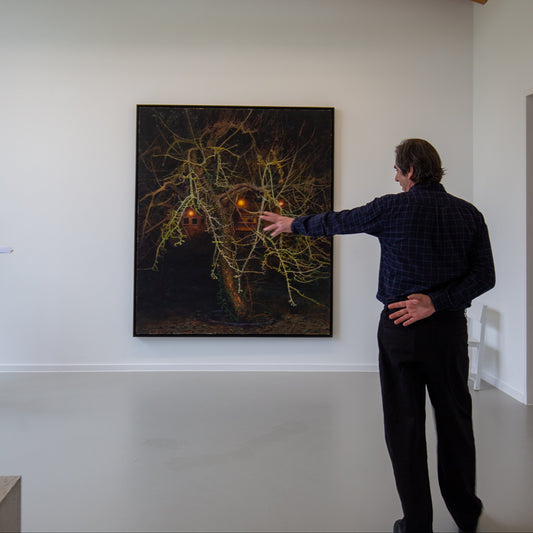 Der Küsntler Dimitris Tzamouranis steht erläuternd vor seinem Bild mit dem Titel Der Baum (Ratzeburg)