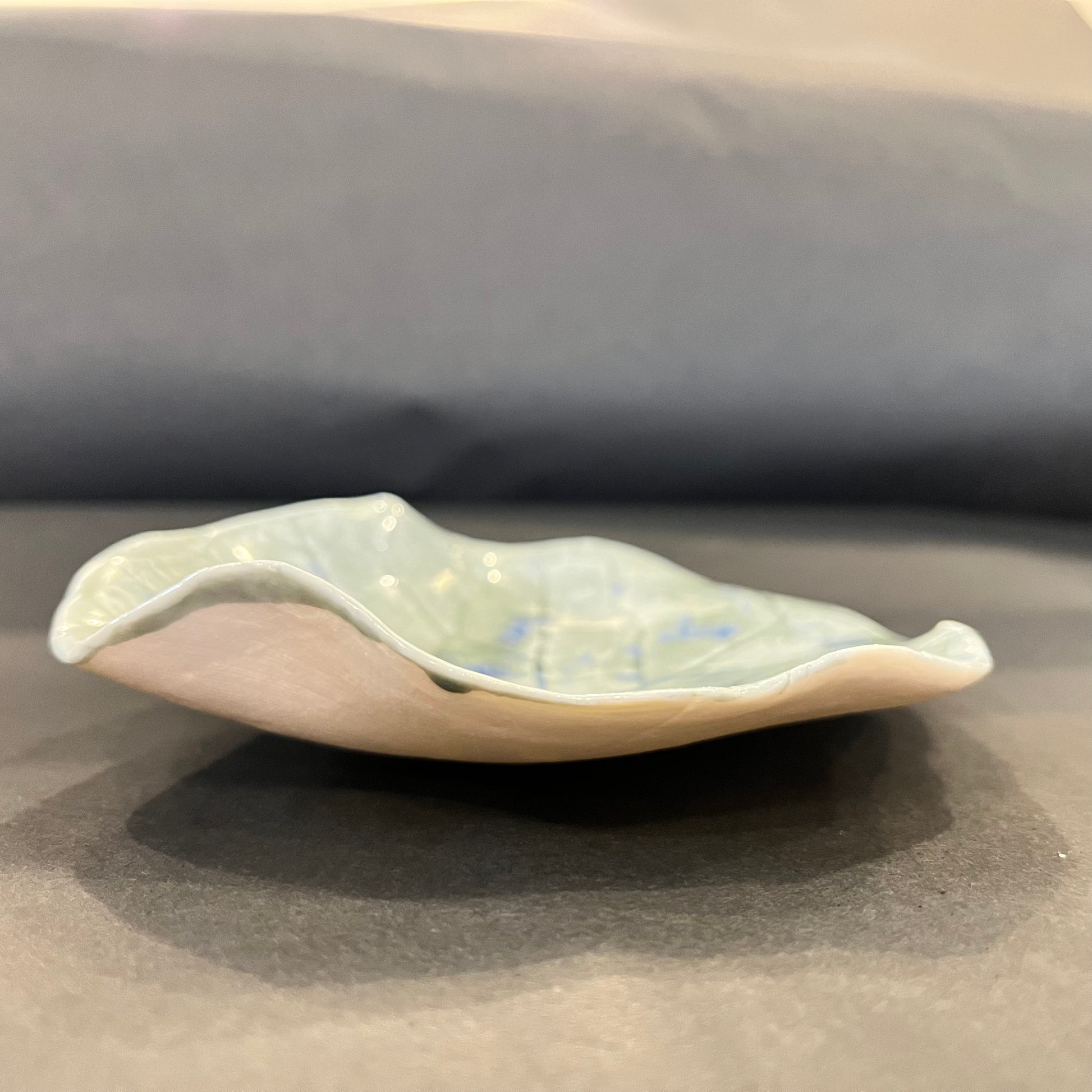 Seitenansicht einer Nymphaea Grey Porzellanschale mit organisch gewelltem Rand und flacher, handgeformter Silhouette.