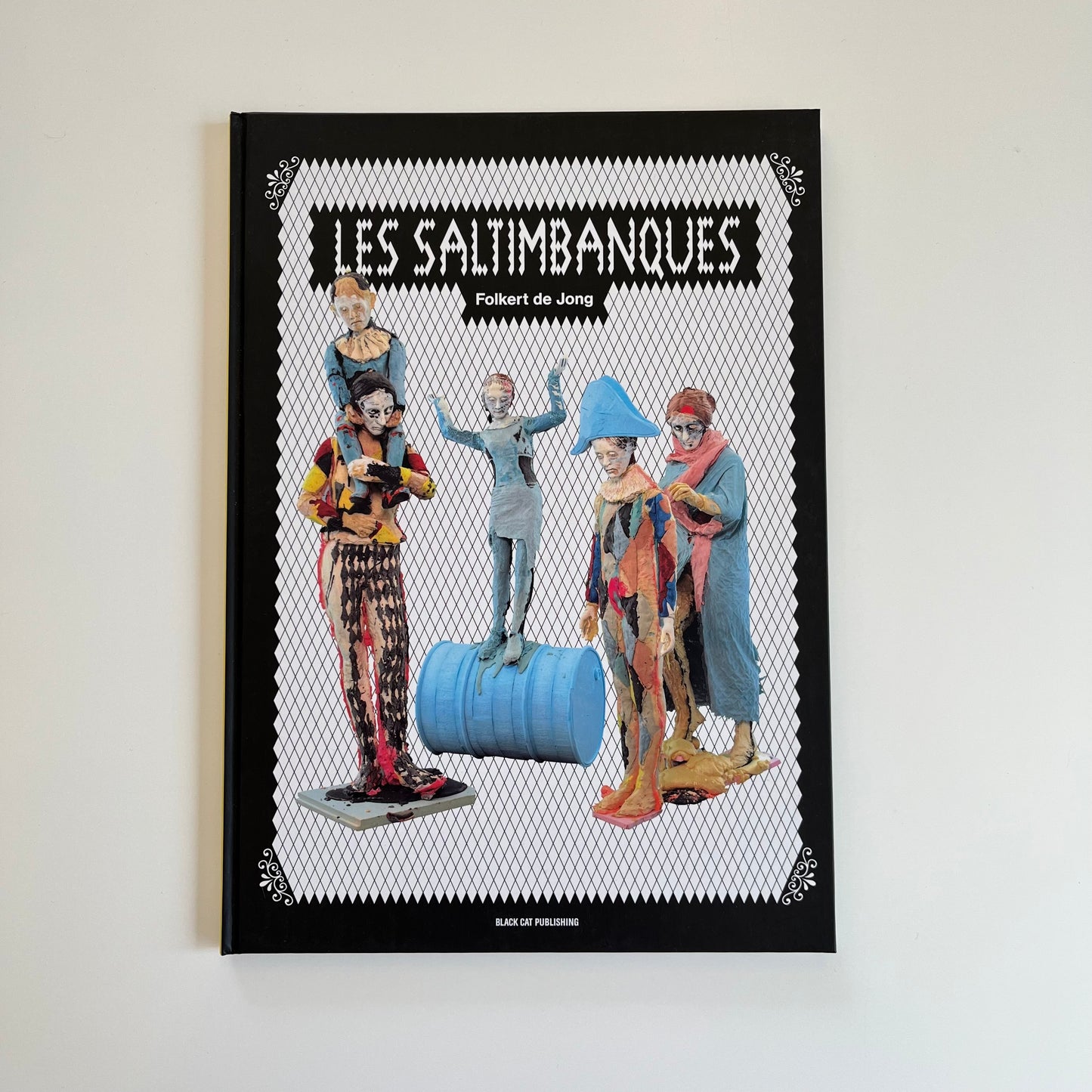 Katalog "Les Saltimbanques" von Folkert de Jong, erhältlich im WAI Sore -farbig illustriertes Buchcover mit Skulpturen