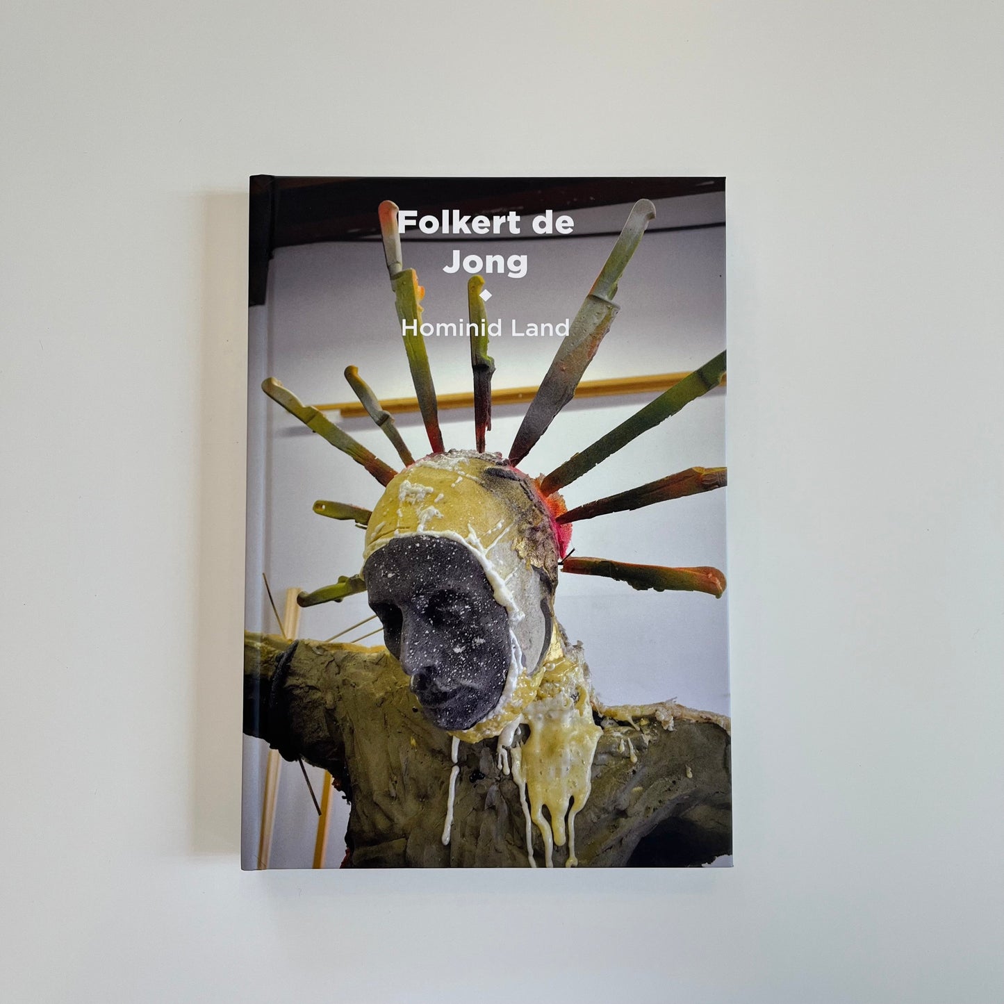 Kunstkatalog "Hominid Land" von Folkert de Jong, erhältlich im WAI Store. Farbig illustriertes Hardcover mit Skulptur